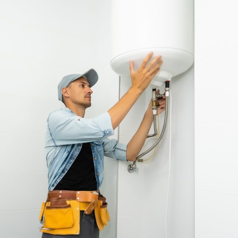 Technician servicing and securing a white Aprilaire whole-home humidifier unit on a residential HVAC furnace duct system.
