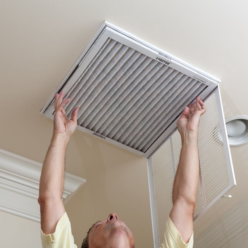 Reaching up to change a dirty ceiling air return filter.